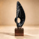 Laying bare the textures of hand-carved abstract marble art, this symbolic black marble sculpture presents an upward-thrusting form for design catalogs.