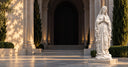 White marble Virgin Mary sculpture with praying hands and rosary displayed at an elegant European chapel entrance